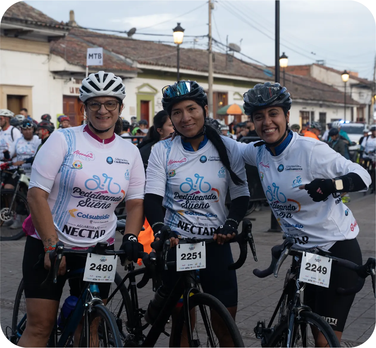 Ciclistas sonriendo con sus números de participación antes de la salida